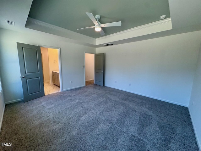 unfurnished bedroom featuring visible vents, a tray ceiling, crown molding, and light colored carpet