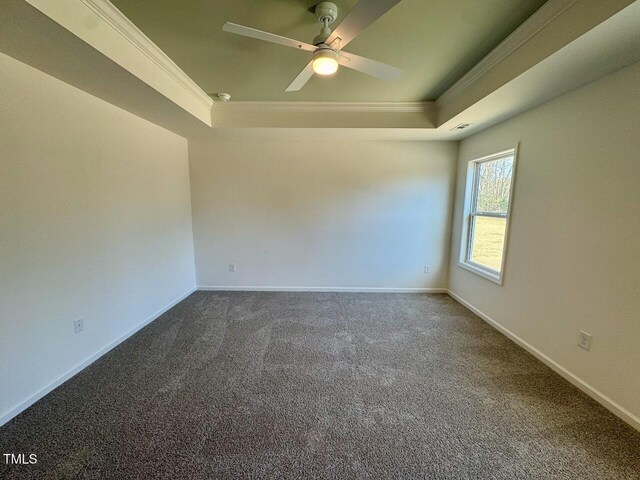 unfurnished room featuring ornamental molding, dark colored carpet, a tray ceiling, and baseboards