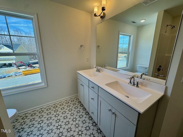 bathroom with double vanity, a sink, toilet, and baseboards