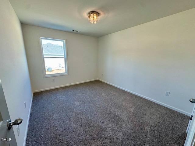 unfurnished room with dark colored carpet, visible vents, and baseboards