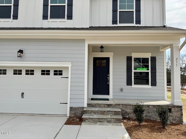 doorway to property with covered porch, board and batten siding, and a garage