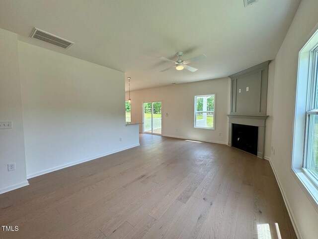 235 Grand Griffon Way, Lillington, NC 27546 - unfurnished living room with wood finished floors, ceiling fan, a large fireplace, and baseboards