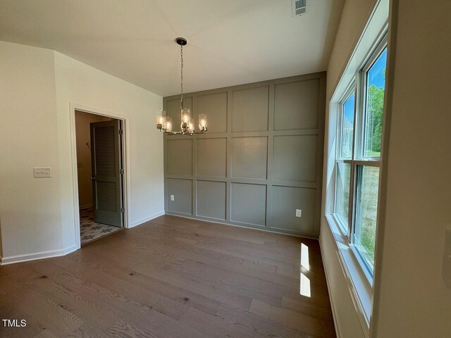 235 Grand Griffon Way, Lillington, NC 27546 - unfurnished dining area with a decorative wall, wood finished floors, a chandelier, and baseboards