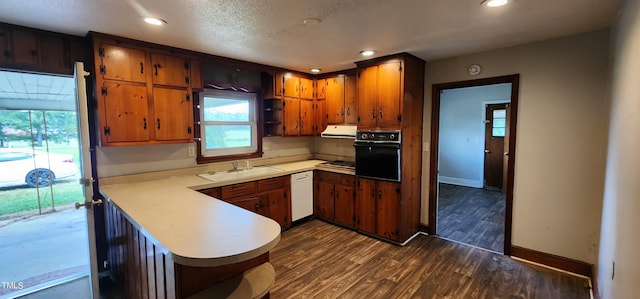 kitchen featuring white dishwasher, sink, kitchen peninsula, black oven, and dark hardwood / wood-style flooring