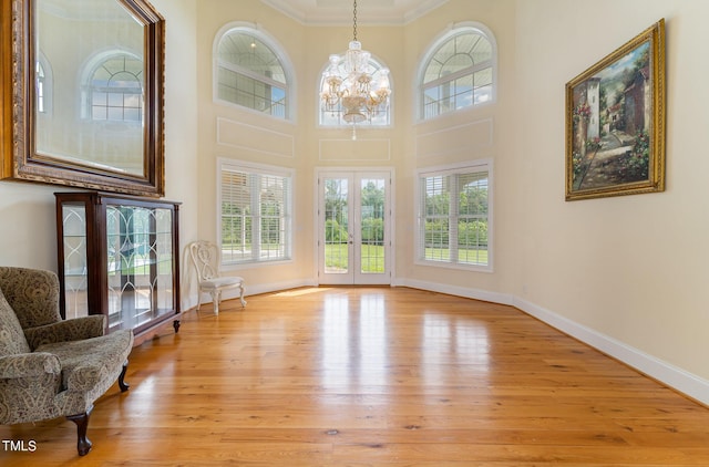 interior space with a healthy amount of sunlight, light wood-type flooring, ornamental molding, and an inviting chandelier