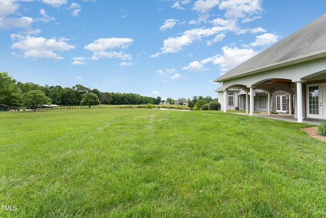 view of yard with french doors and a rural view
