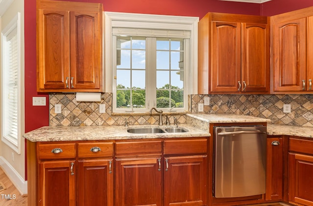 kitchen with dishwasher, sink, hardwood / wood-style flooring, light stone countertops, and tasteful backsplash