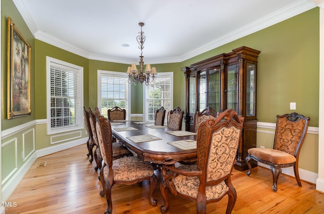 dining area featuring an inviting chandelier, crown molding, and light hardwood / wood-style flooring