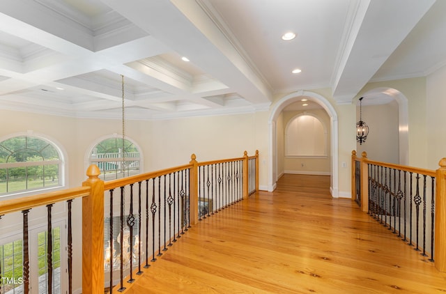 corridor featuring beam ceiling, crown molding, light hardwood / wood-style floors, and an inviting chandelier