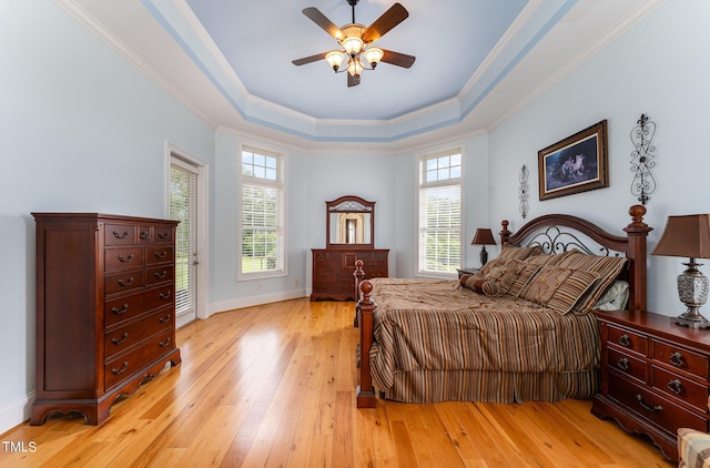 bedroom featuring ornamental molding, light hardwood / wood-style floors, ceiling fan, and a tray ceiling