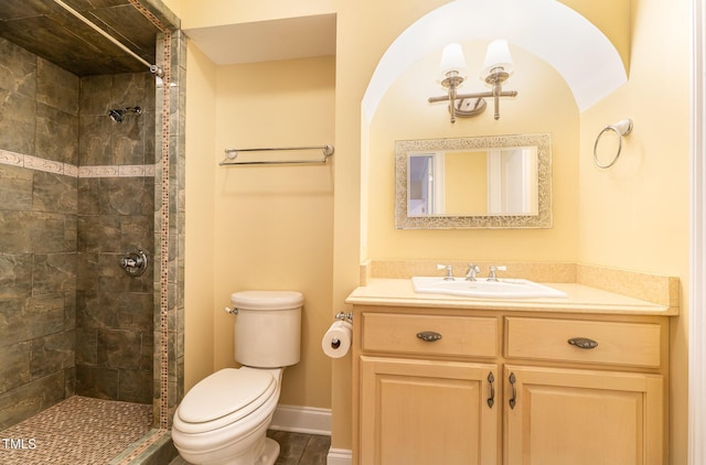 bathroom with a tile shower, vanity, and toilet
