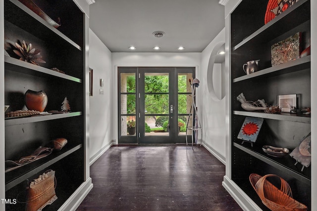 doorway with built in shelves, visible vents, baseboards, and wood finished floors