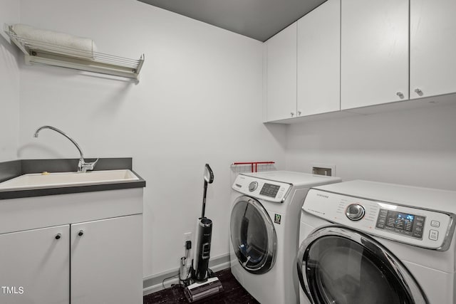 washroom featuring baseboards, a sink, dark wood-style floors, cabinet space, and washing machine and clothes dryer