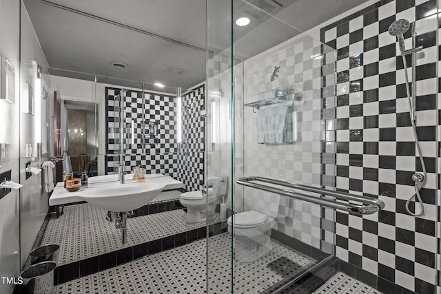 bathroom featuring tile walls, a shower with shower door, toilet, and tile patterned flooring