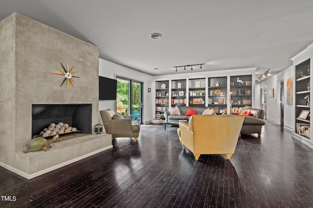 living room featuring visible vents, hardwood / wood-style flooring, baseboards, and a large fireplace