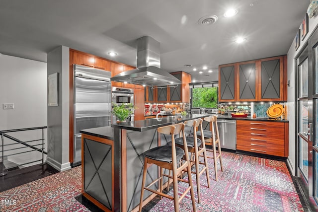 kitchen with dark countertops, island exhaust hood, recessed lighting, stainless steel appliances, and backsplash