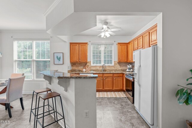 kitchen with white fridge with ice dispenser, electric stove, ceiling fan, and decorative backsplash