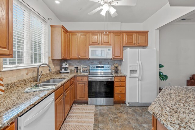 kitchen with ceiling fan, light stone counters, sink, white appliances, and tasteful backsplash