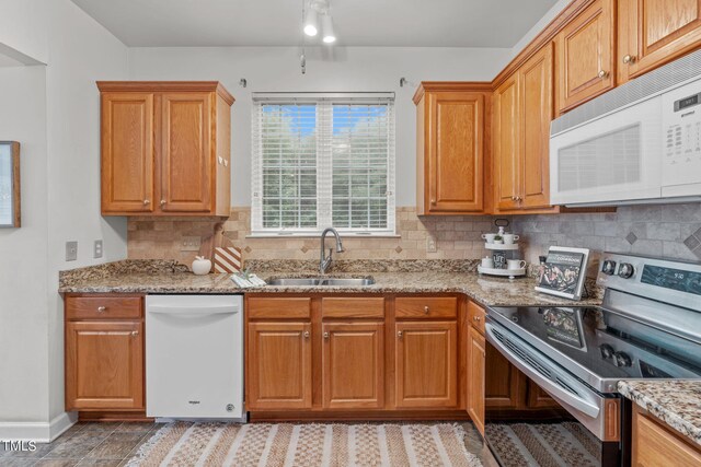 kitchen featuring white appliances, sink, light stone counters, and tasteful backsplash