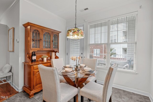 dining space featuring ornamental molding, plenty of natural light, and dark tile patterned floors