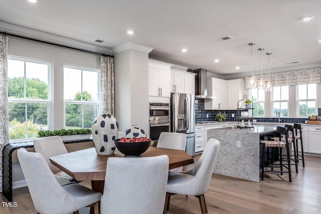 dining area with an inviting chandelier, crown molding, sink, and light hardwood / wood-style flooring