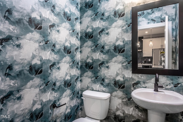 bathroom with decorative backsplash, sink, and toilet