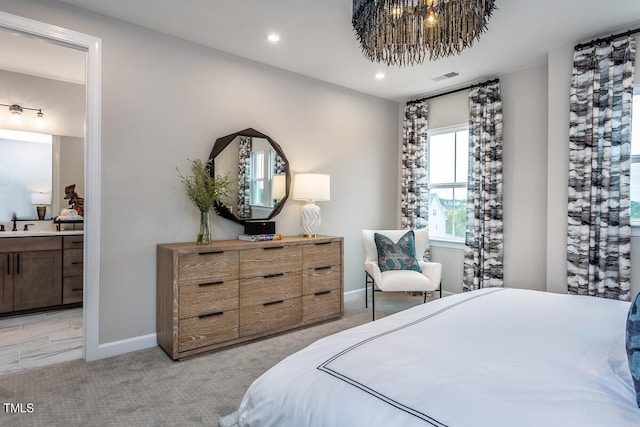 carpeted bedroom featuring a notable chandelier, ensuite bath, and sink