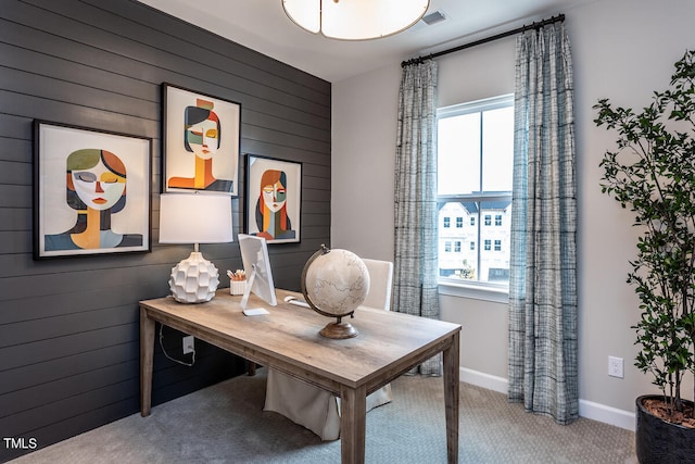 carpeted office space featuring wooden walls