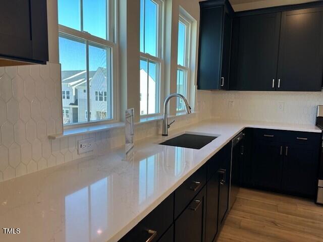 kitchen featuring dark cabinetry, a wealth of natural light, and a sink