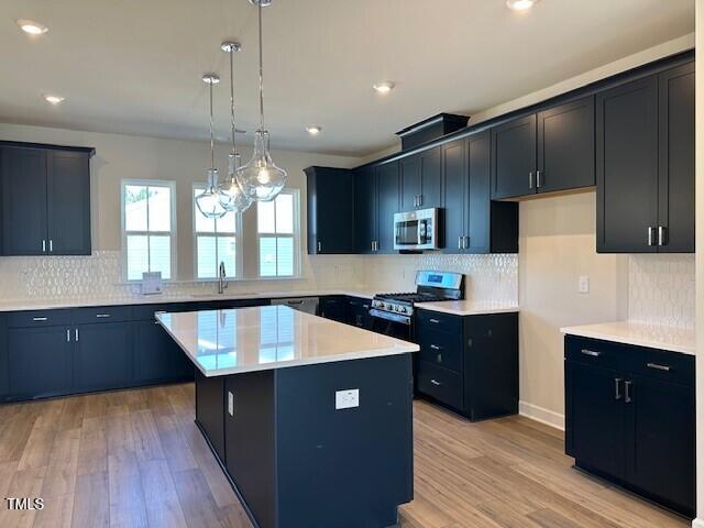 kitchen featuring light wood-style floors, appliances with stainless steel finishes, a center island, and light countertops