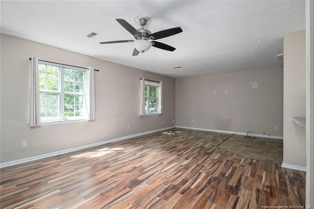 unfurnished room with ceiling fan, dark hardwood / wood-style flooring, and a textured ceiling