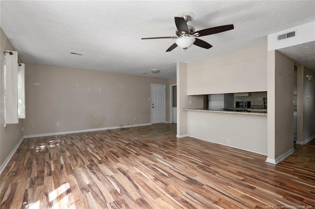 unfurnished living room featuring ceiling fan, wood-type flooring, and a textured ceiling