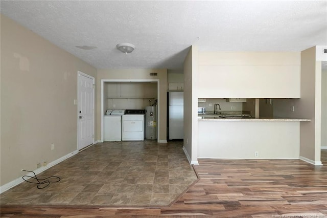 kitchen featuring washing machine and dryer, water heater, stainless steel fridge, hardwood / wood-style floors, and a textured ceiling