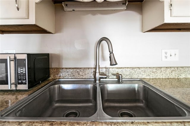 room details with white cabinets, sink, and dark stone counters