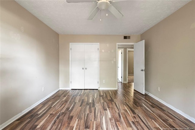 unfurnished bedroom with a textured ceiling, a closet, ceiling fan, and dark hardwood / wood-style floors