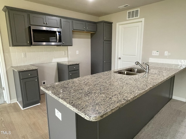 53 Grace Ridge Ct, Benson, NC 27504 - kitchen with visible vents, a sink, light stone counters, stainless steel microwave, and a peninsula