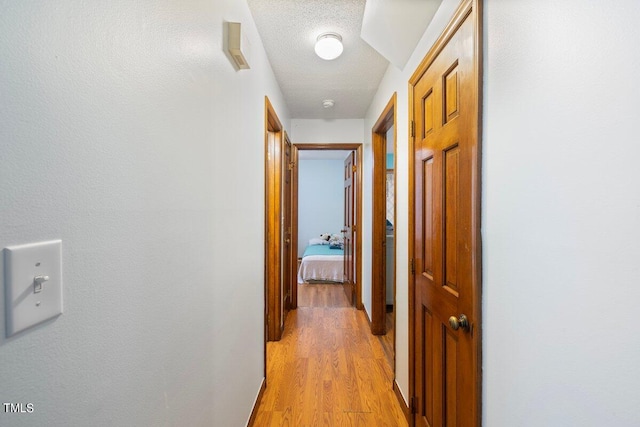 corridor with light hardwood / wood-style flooring and a textured ceiling