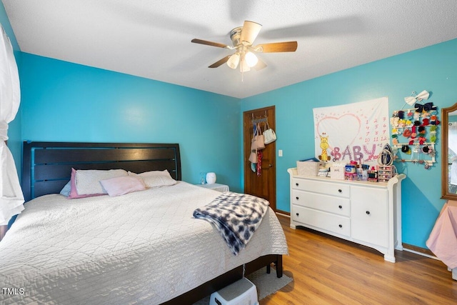 bedroom featuring light hardwood / wood-style flooring, ceiling fan, and a textured ceiling