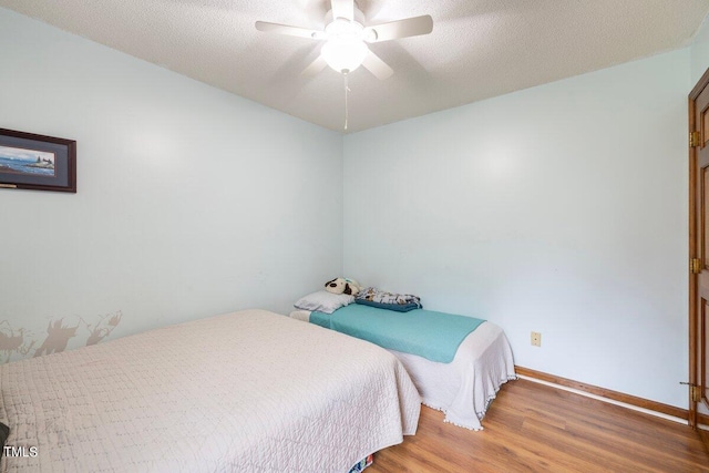 bedroom featuring a textured ceiling, wood-type flooring, and ceiling fan