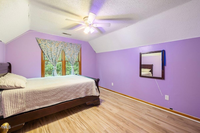 bedroom with ceiling fan, a textured ceiling, vaulted ceiling, and hardwood / wood-style flooring