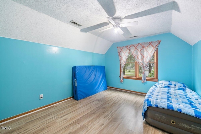 bedroom featuring a textured ceiling, lofted ceiling, ceiling fan, and light hardwood / wood-style flooring