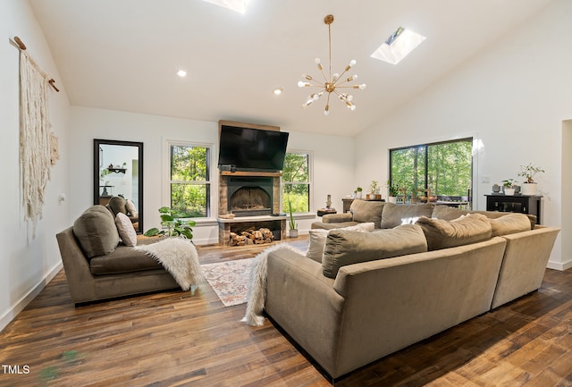 living room featuring a stone fireplace, a skylight, hardwood / wood-style flooring, and a chandelier