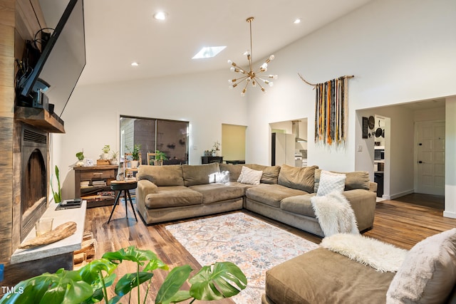 living room with light hardwood / wood-style floors, high vaulted ceiling, a notable chandelier, and a skylight