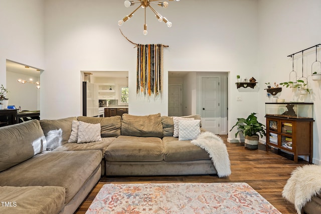 living room with a towering ceiling, dark hardwood / wood-style floors, and a chandelier