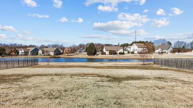 view of pool with fence, a water view, and a residential view