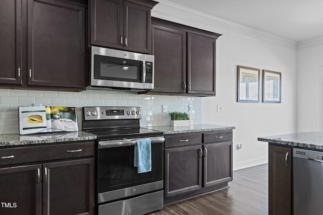 kitchen featuring dark wood finished floors, stainless steel appliances, decorative backsplash, ornamental molding, and light stone countertops