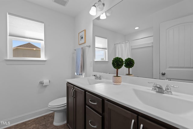 full bathroom featuring double vanity, toilet, visible vents, and a sink