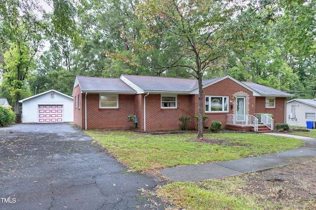 single story home featuring a garage, an outbuilding, brick siding, and aphalt driveway