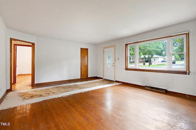 unfurnished room featuring visible vents, hardwood / wood-style flooring, and baseboards