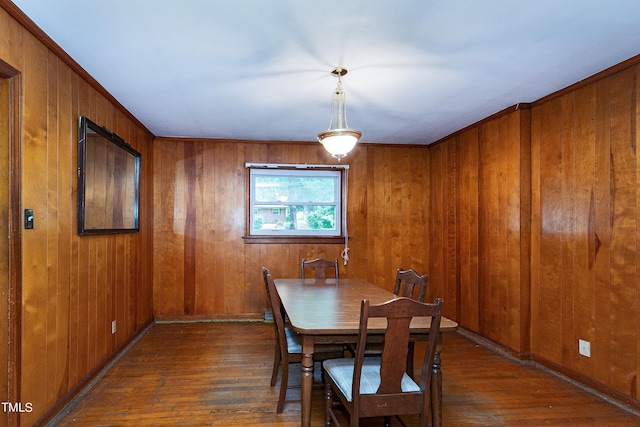 dining space featuring wood walls, baseboards, and wood finished floors